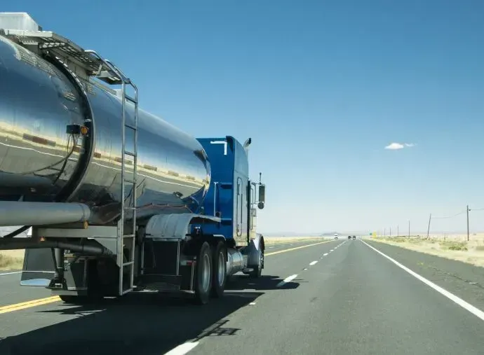 A blue and silver semi truck is driving down a highway.