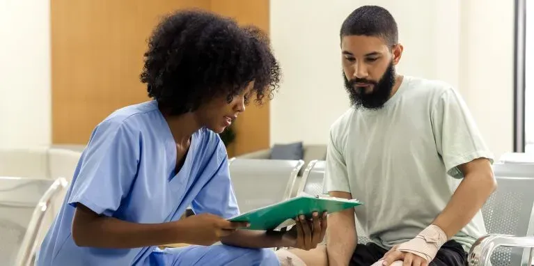A nurse is talking to a patient in a hospital room.