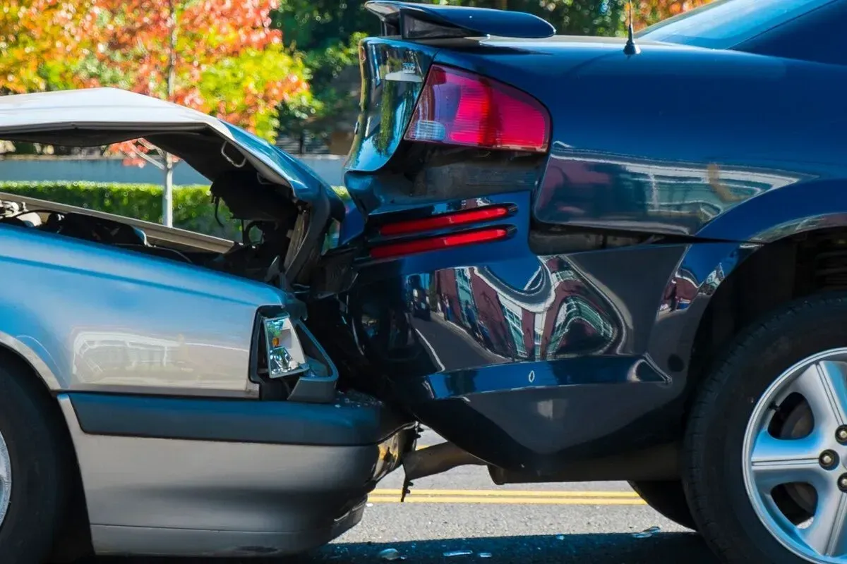 Two cars are involved in a car accident on the side of the road.