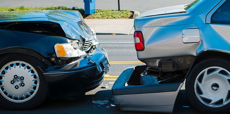 Two cars are involved in a car accident on the side of the road.
