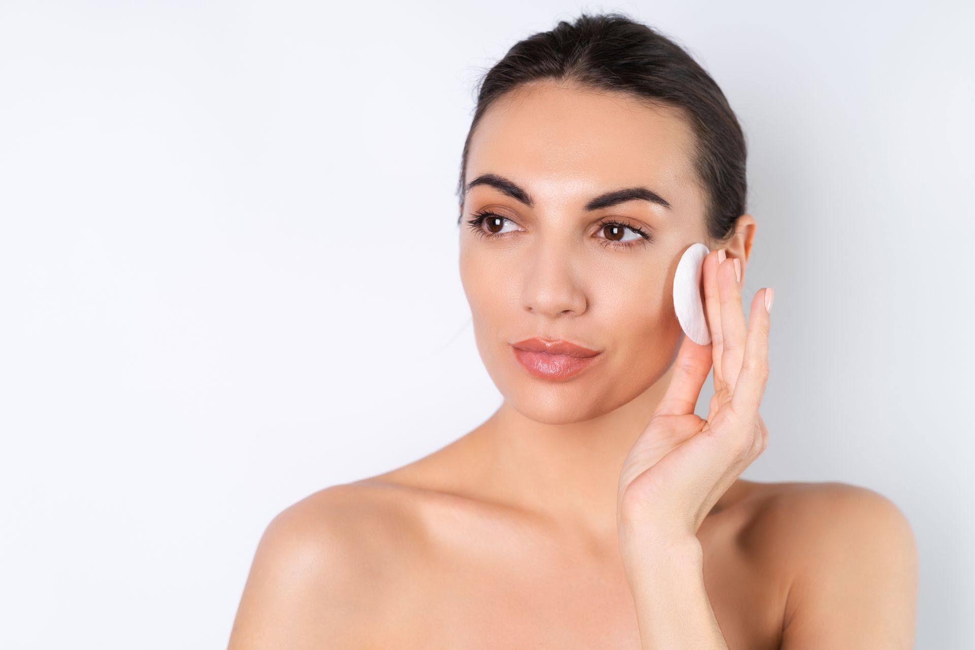 a woman wipes her face with a cotton pad