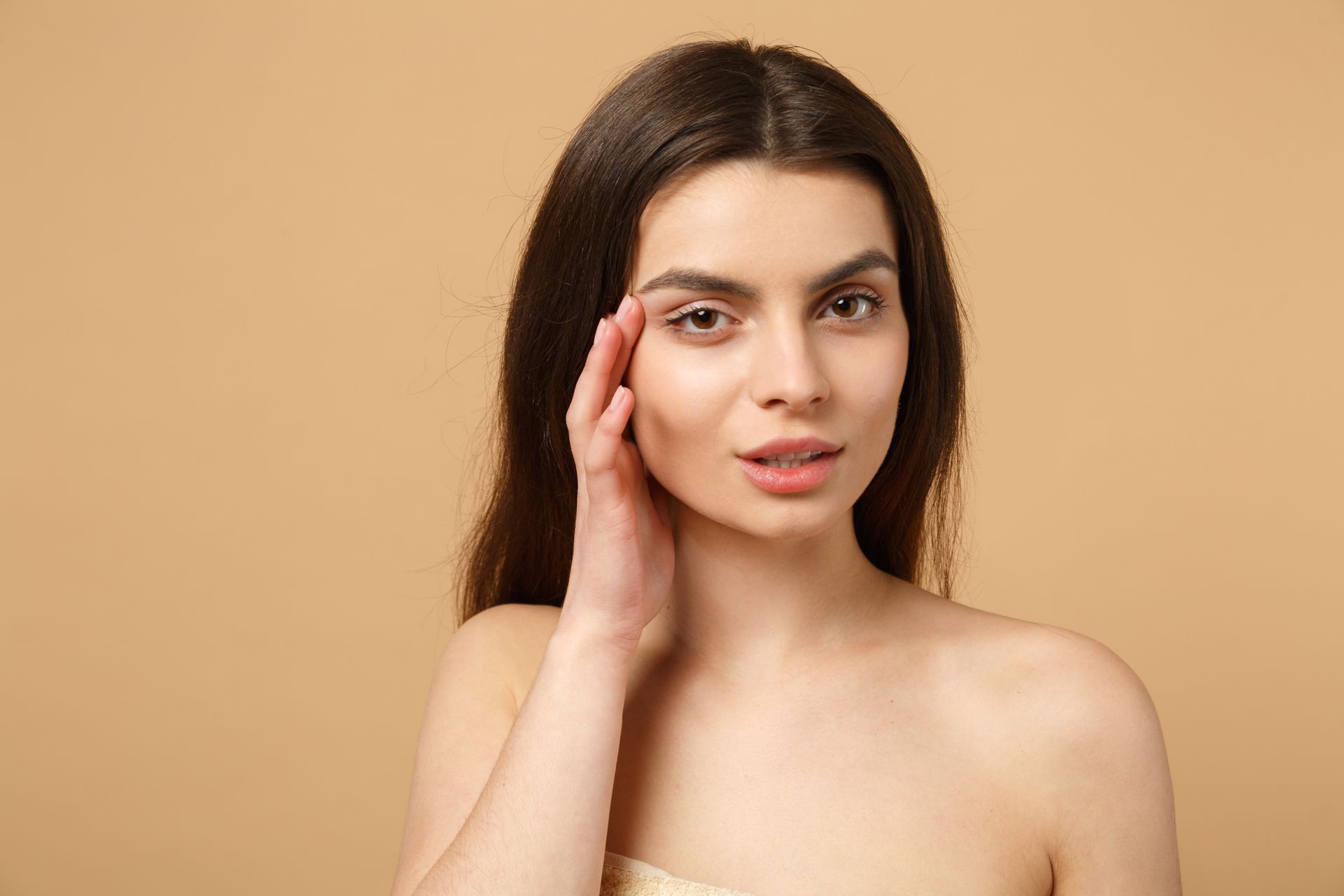 A woman is touching her face with her hand and looking at the camera.