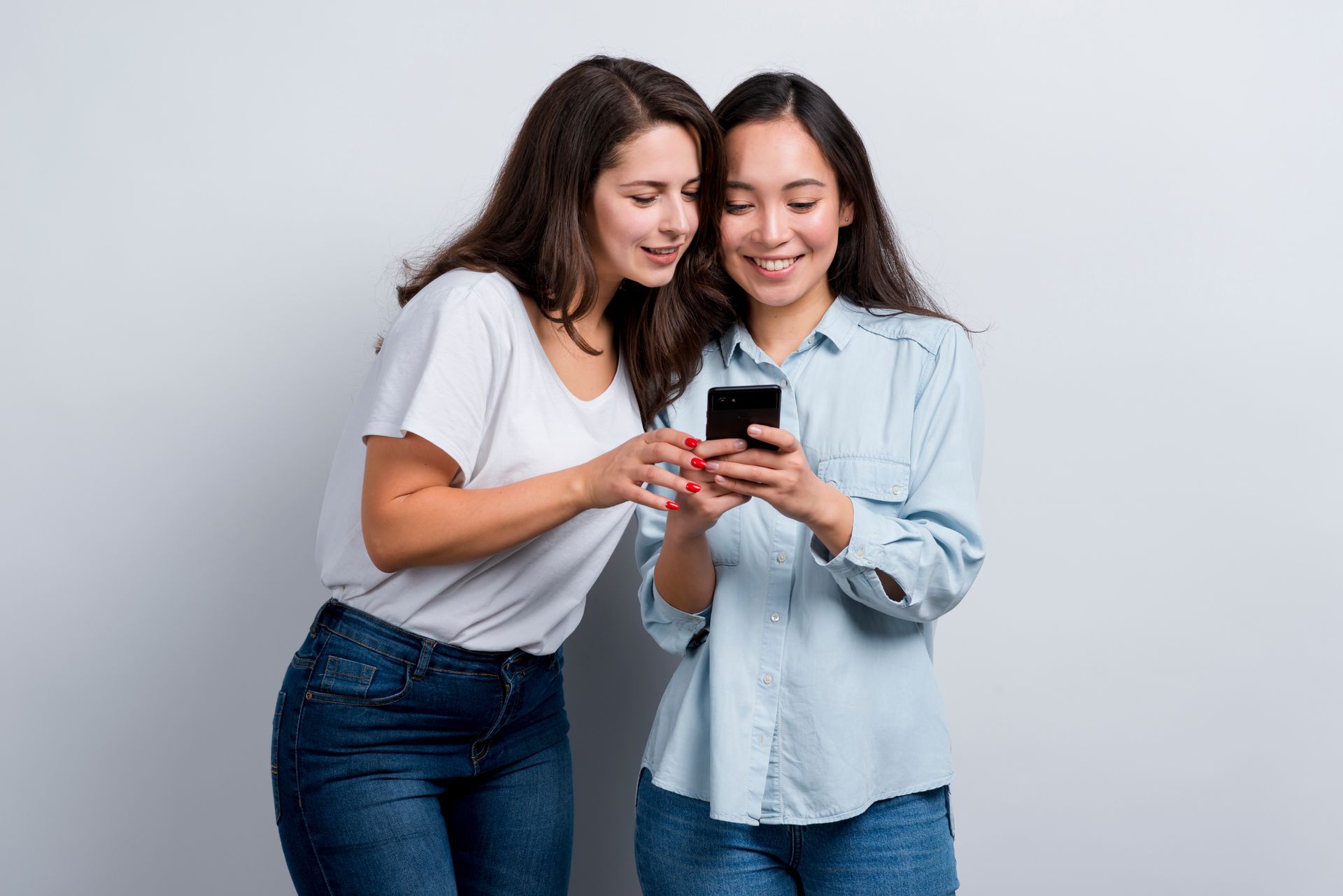 Two women are looking at a cell phone in a park.
