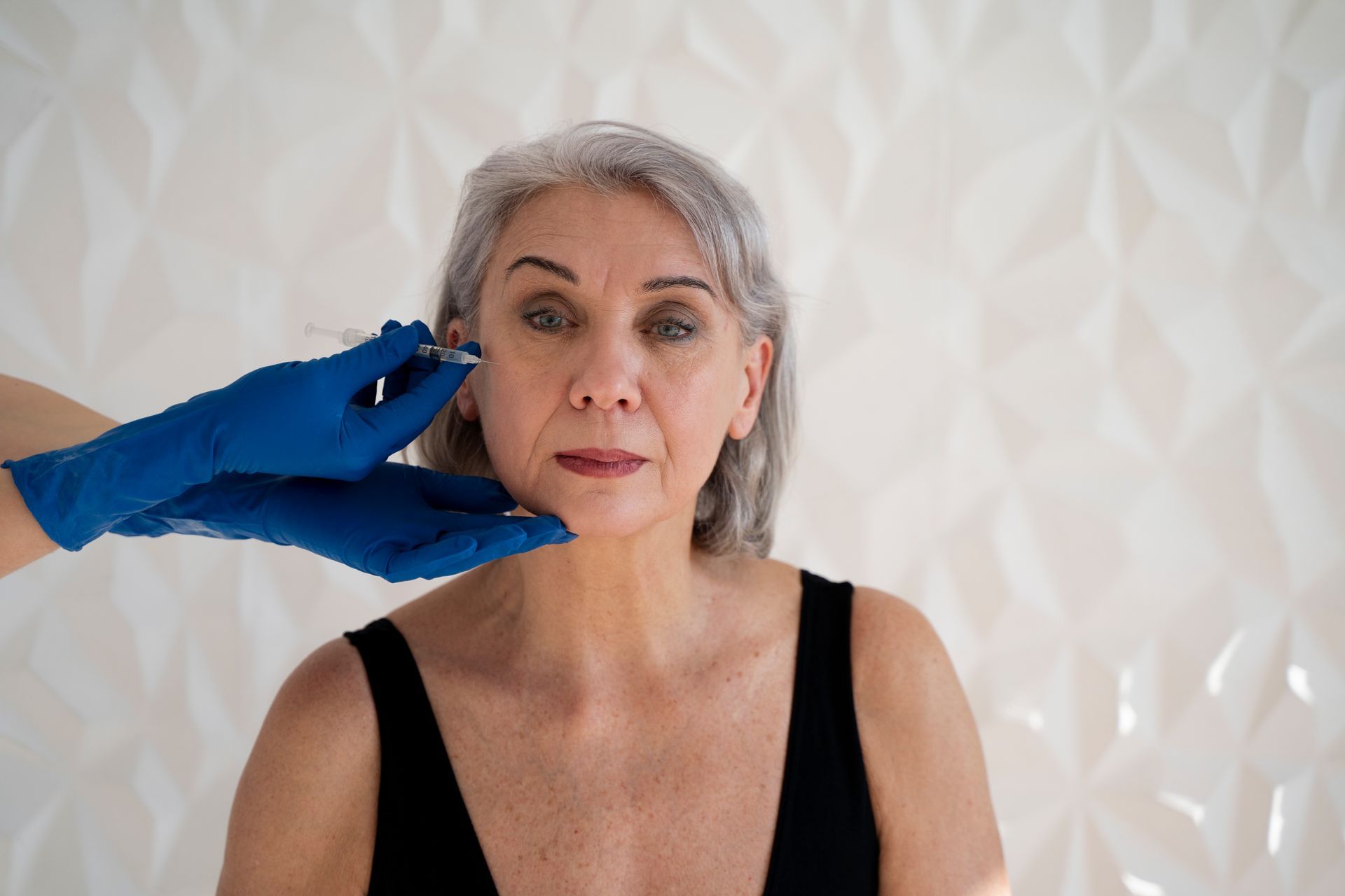 An older woman is getting a botox injection in her face.