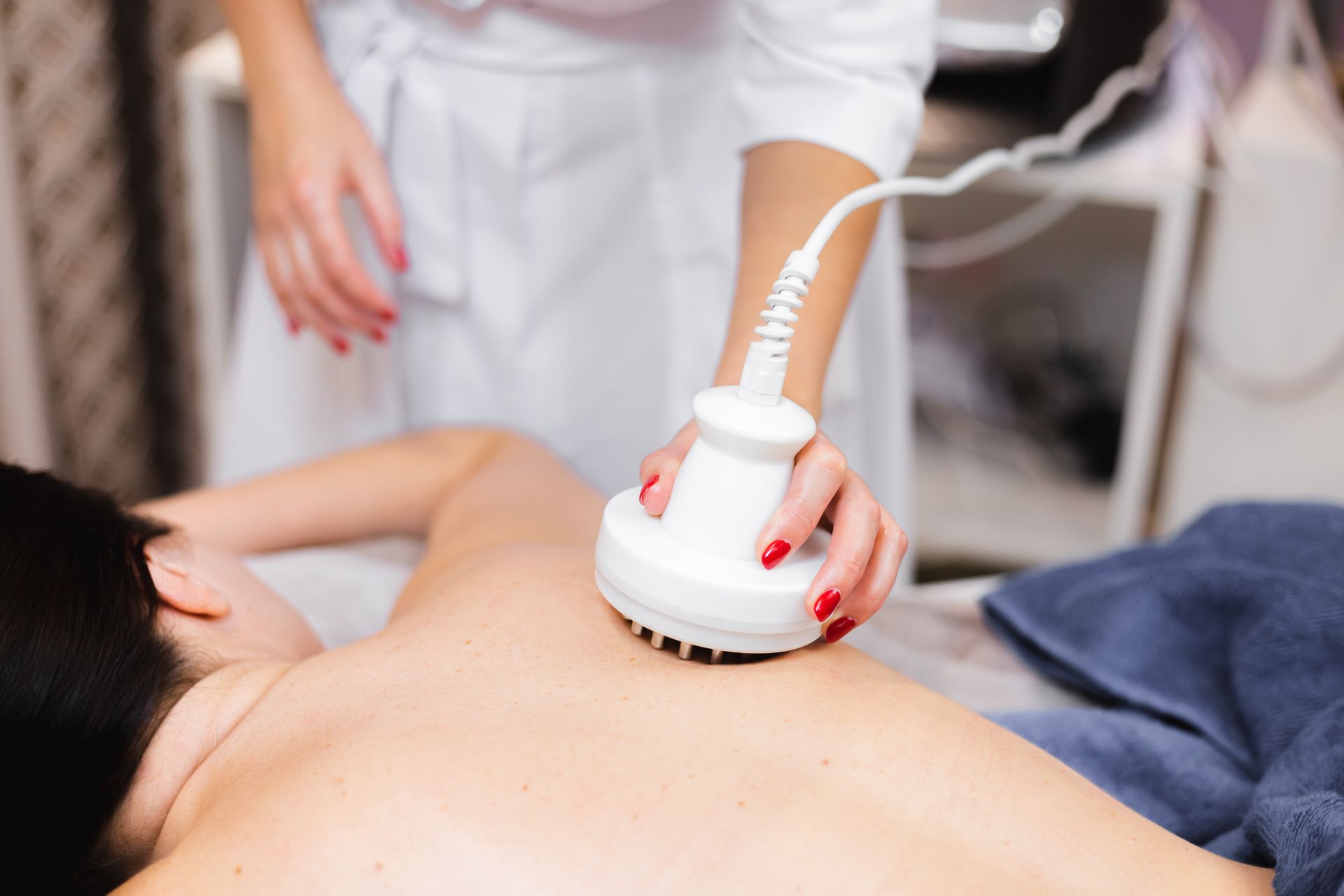 A woman is getting a massage with a machine on her back.