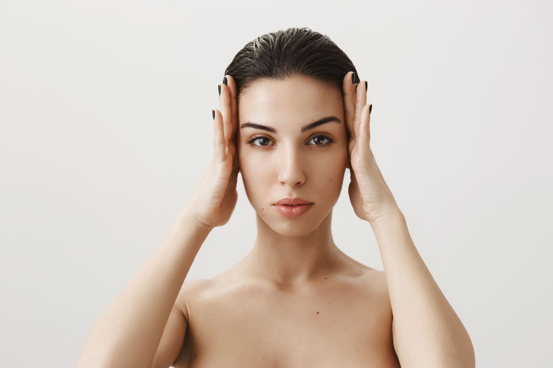 a woman without a shirt holds her hands to her face