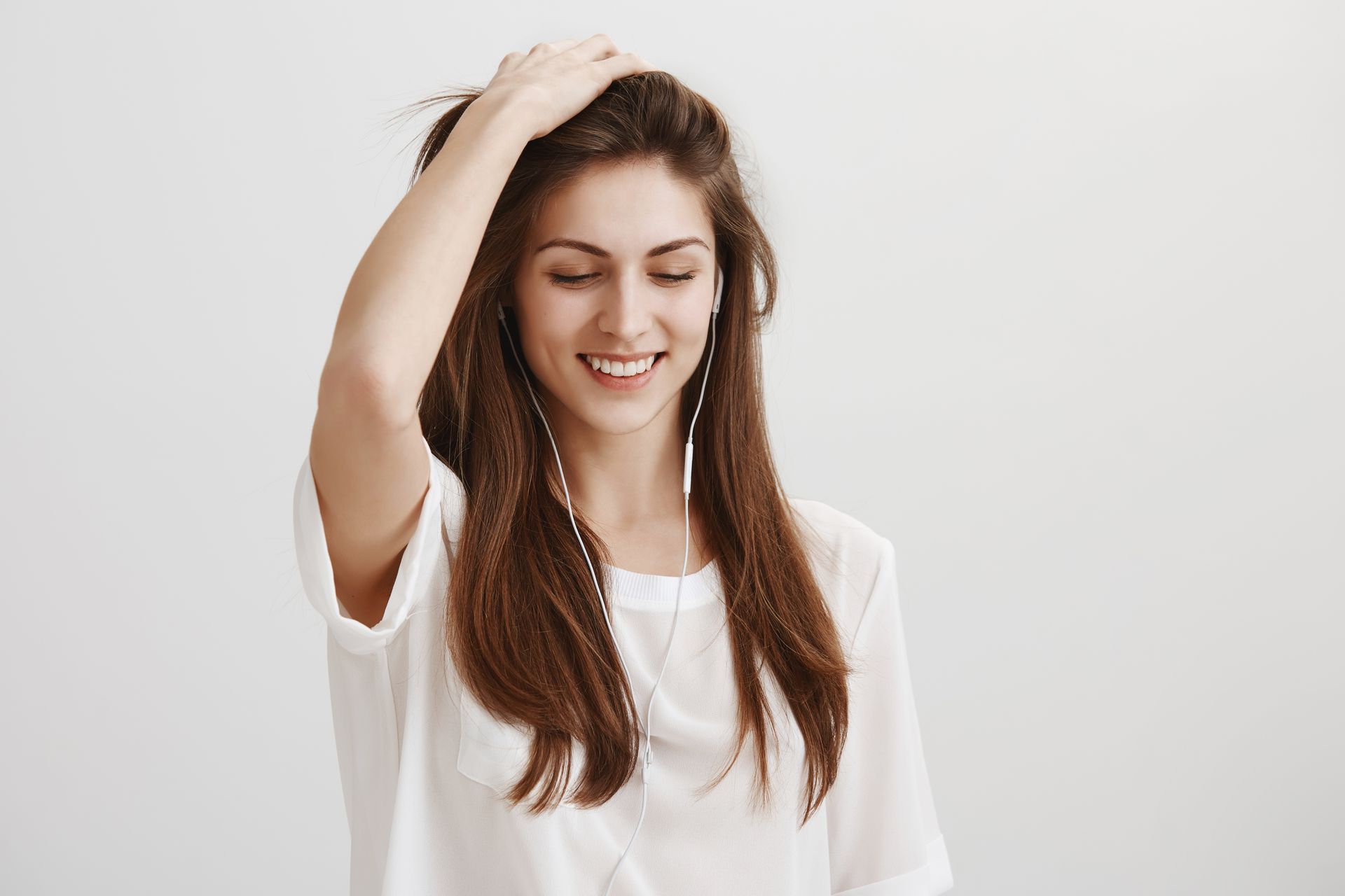 a woman in a yellow tank top is smiling and touching her hair