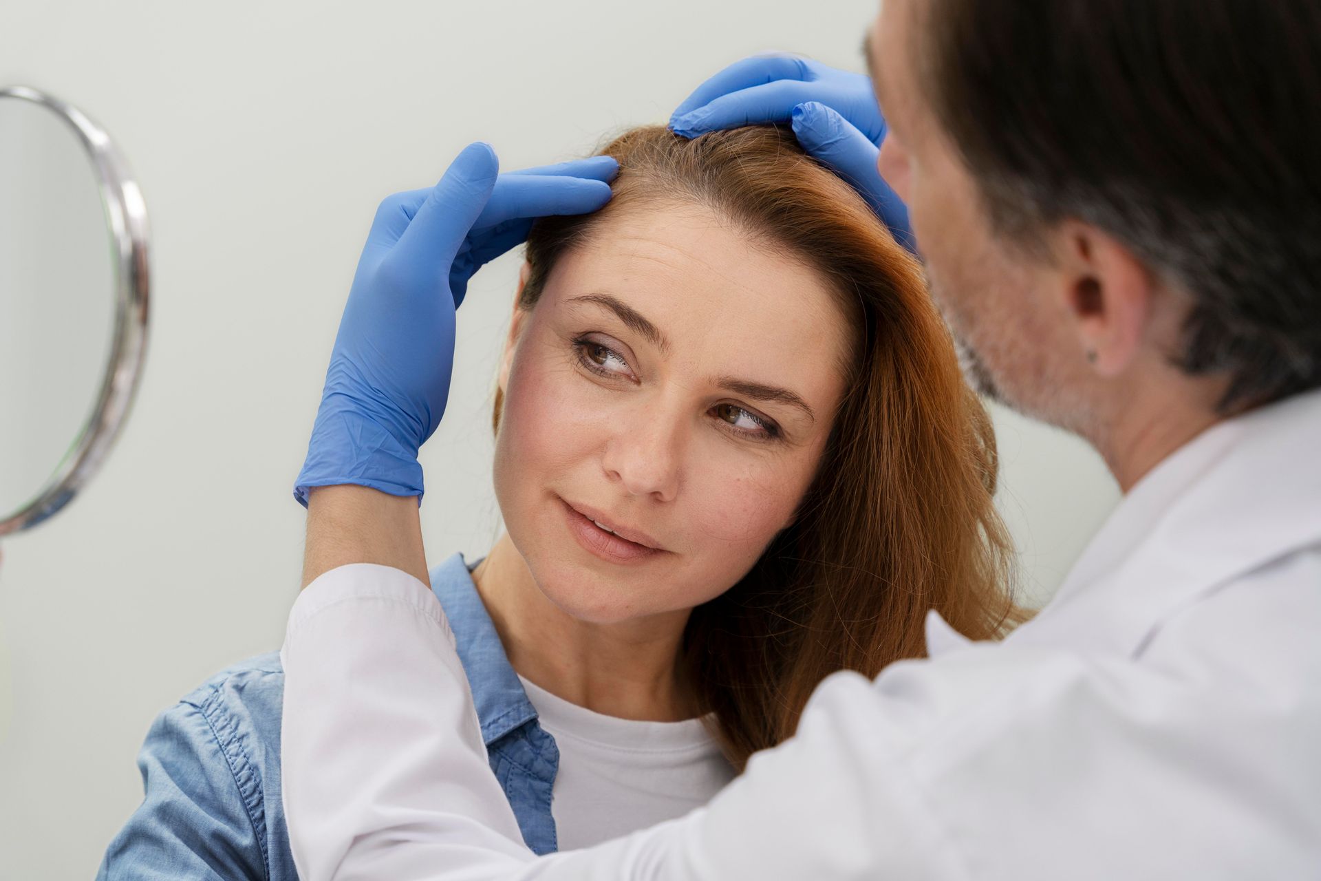 a doctor examines a woman 's hair in front of a mirror