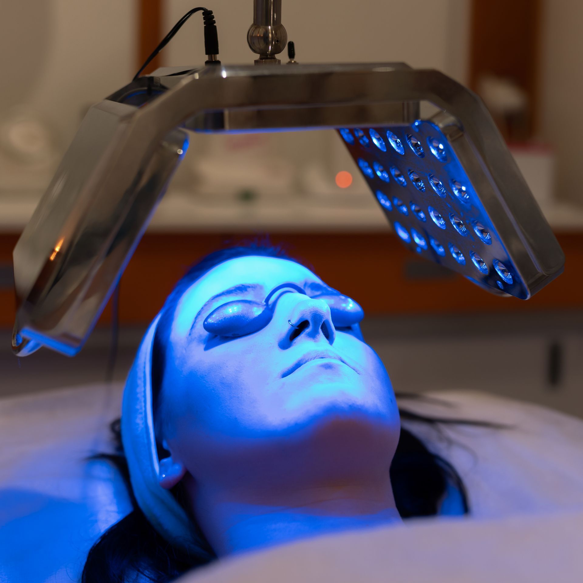 A woman is getting a blue light treatment on her face