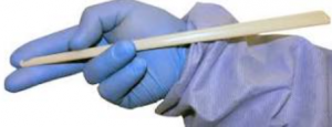 Gloved hand holding a wooden swab.