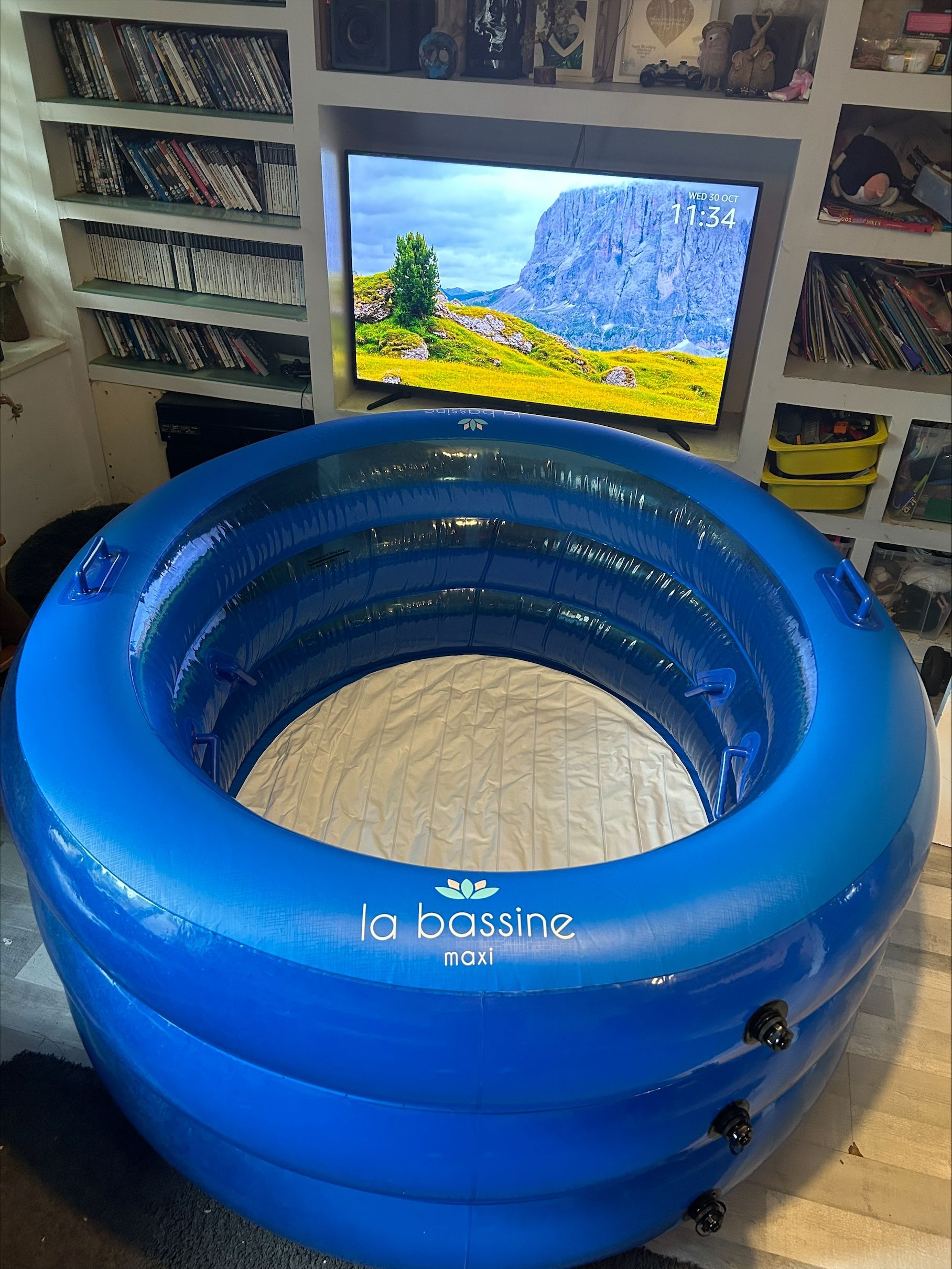 Blue inflatable birth pool indoors, TV in background.