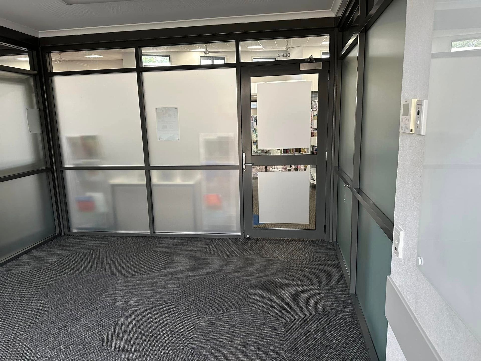 An Empty Room With Frosted Glass Walls and a Door — Wide Bay Tinting in South Kolan, QLD