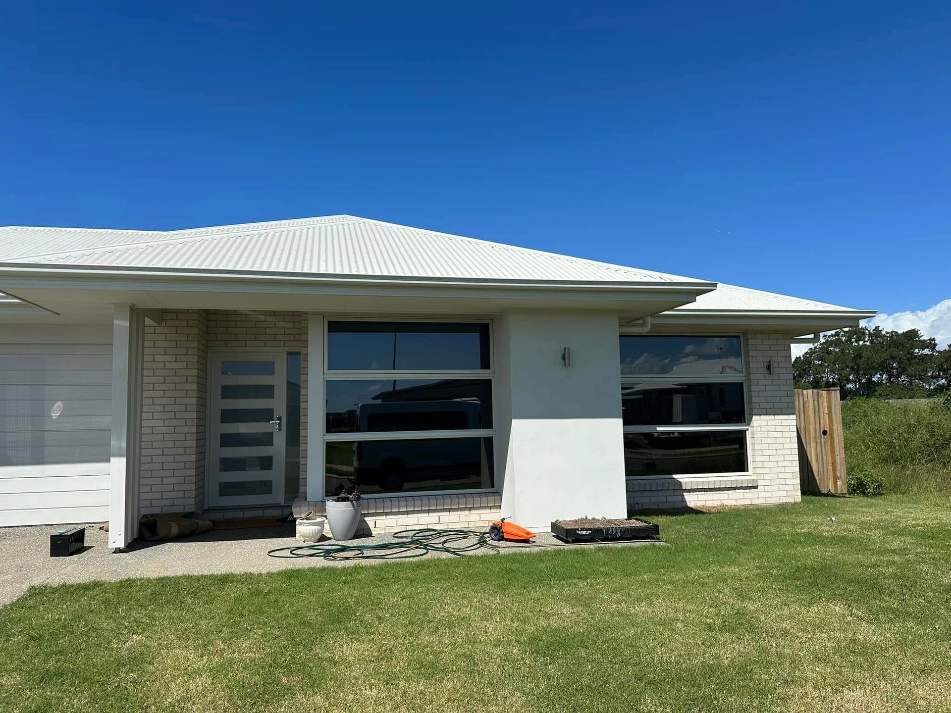 Light-Colored House With Large Windows Under a Blue Sky — Wide Bay Tinting in South Kolan, QLD