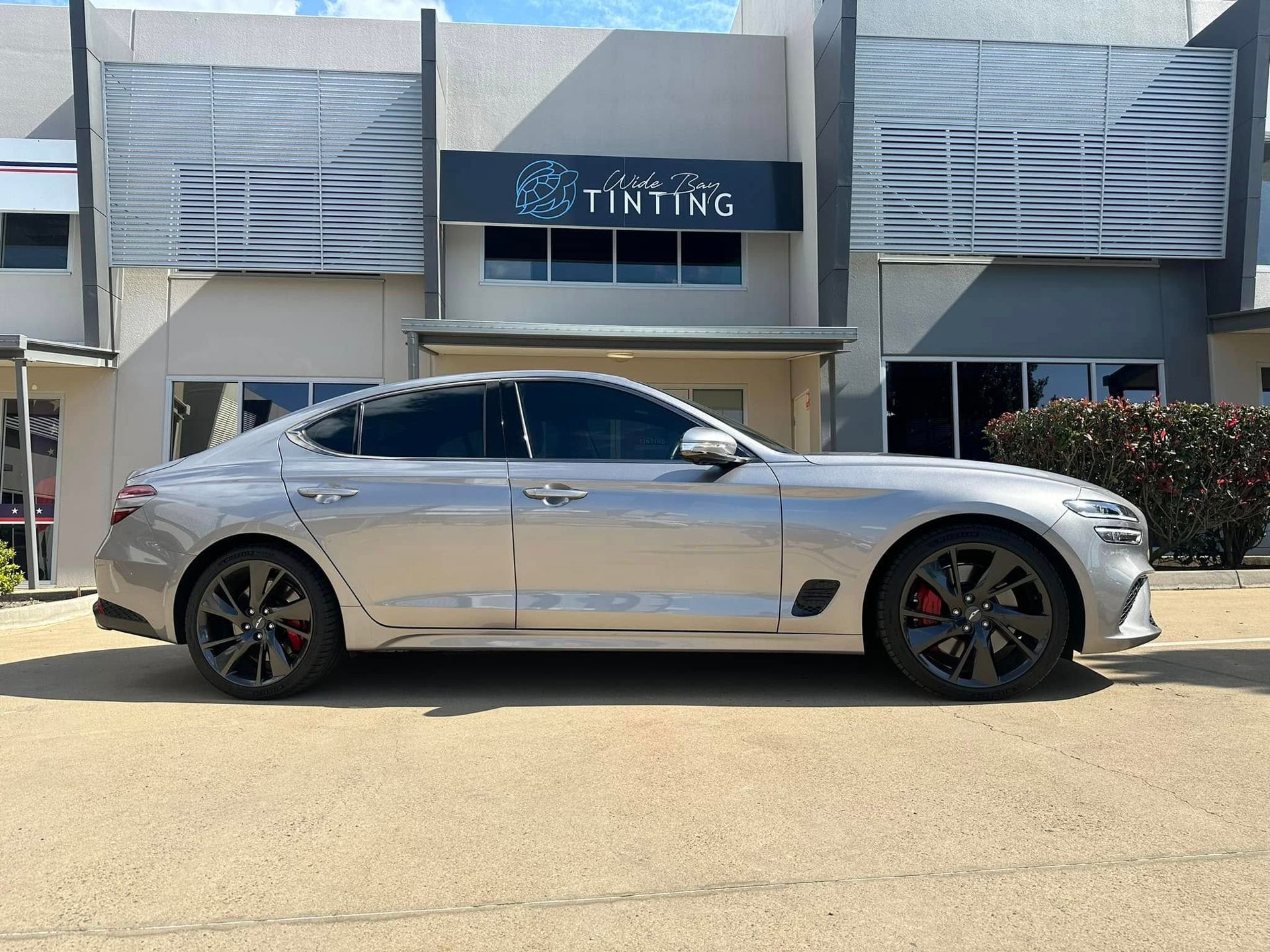 Silver car with tinted windows parked in front of a 