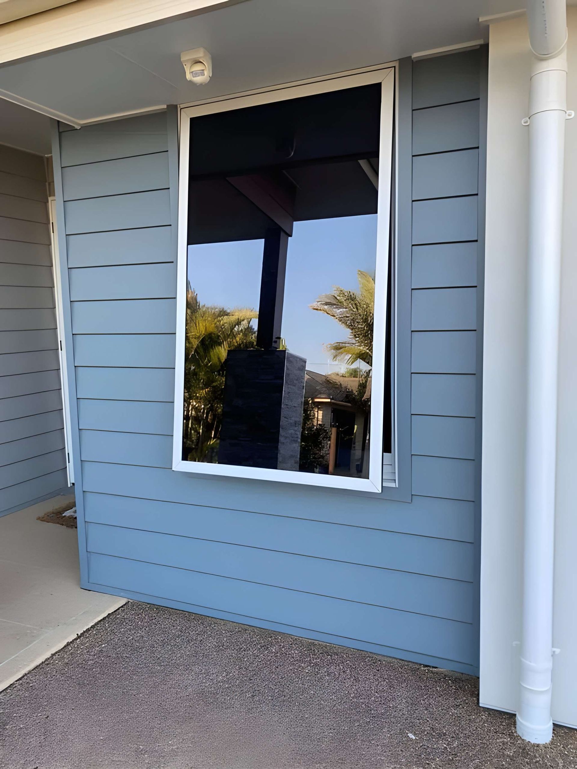 Blue House Exterior With a Large Window Reflecting the Outside — Wide Bay Tinting in Kensington, QLD