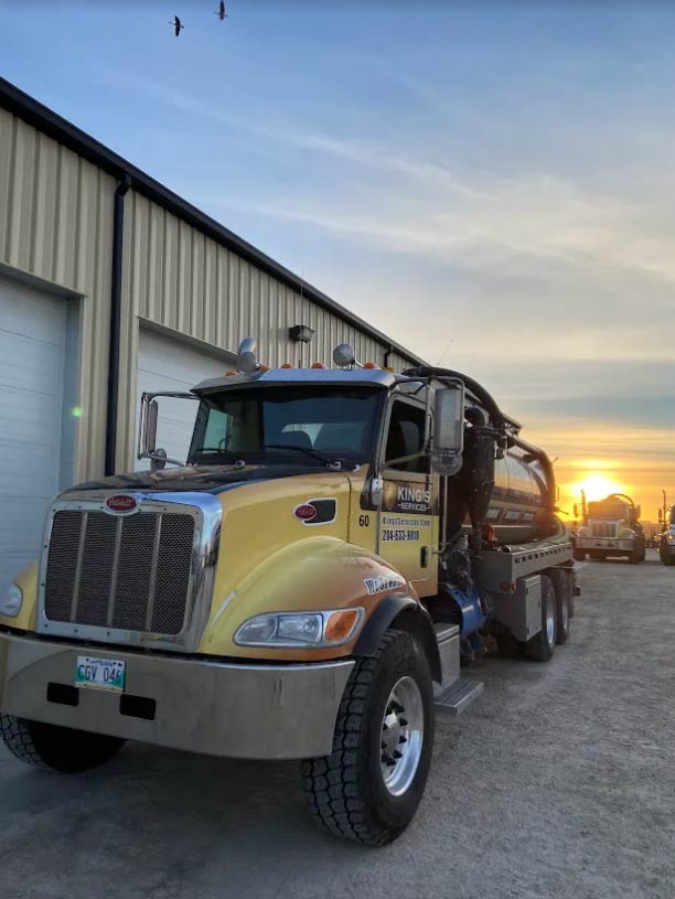 Yellow tanker truck parked outside a building at sunset.