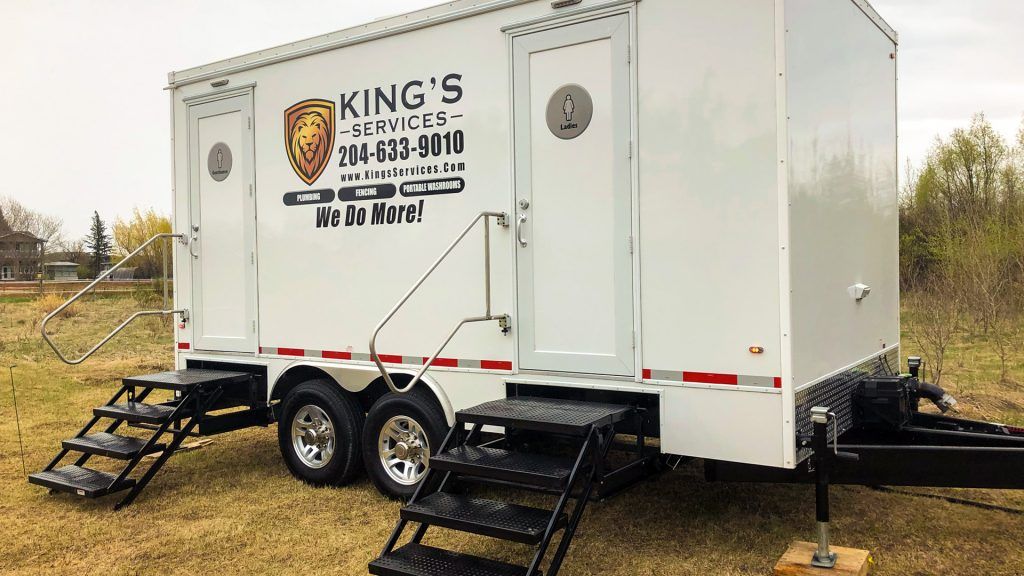 White King’s portable restroom trailer with black steps, parked on grass outdoors.