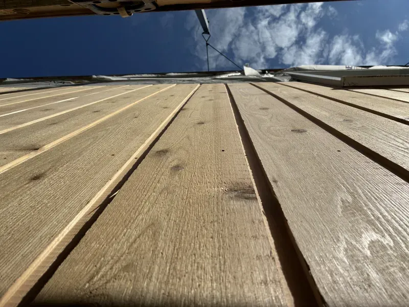 Wooden siding on a building, viewed from a low angle against a blue sky.