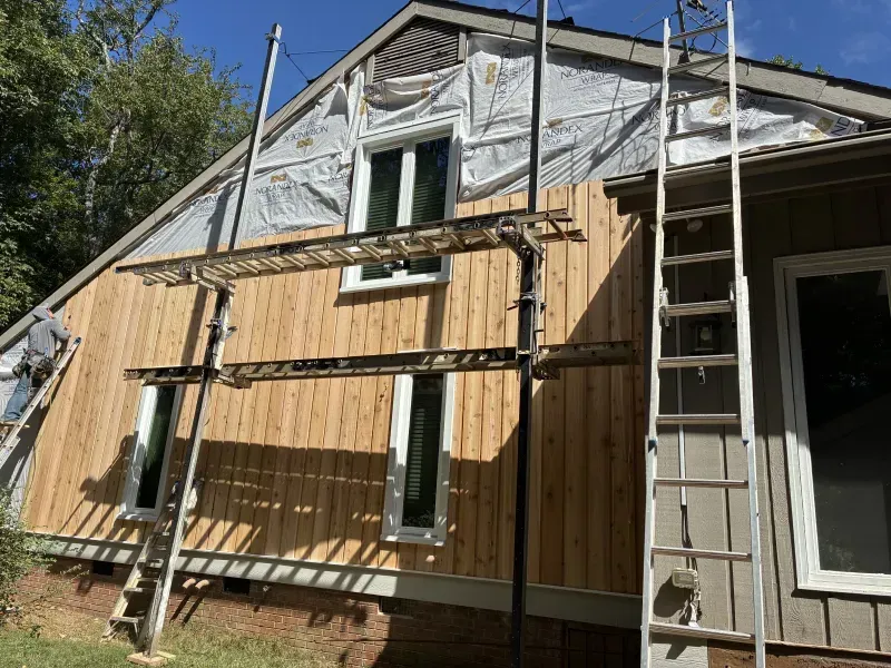 House exterior with new wood siding being installed, scaffolding in place.