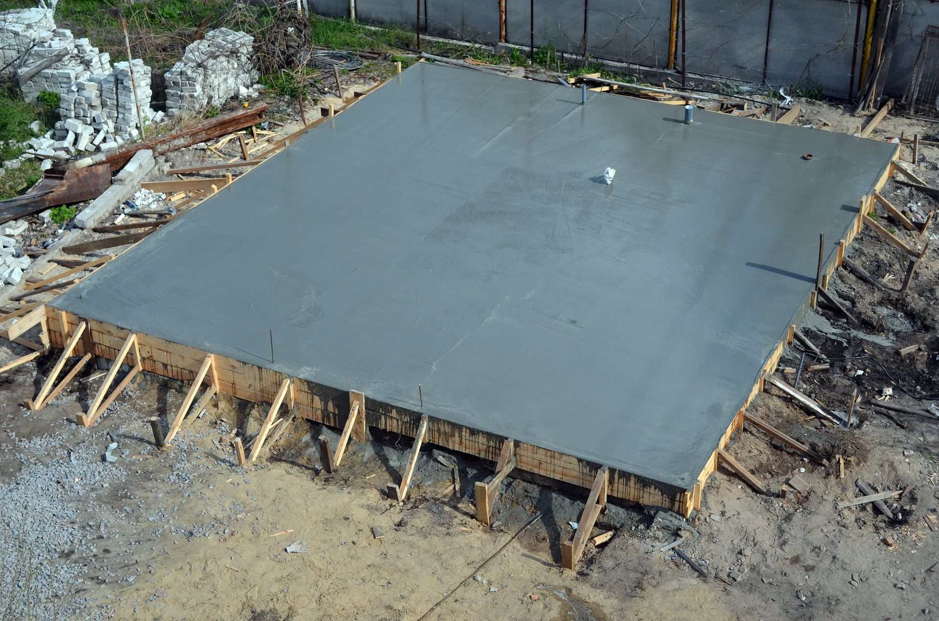 Newly poured concrete slab within a wooden frame, outdoors.