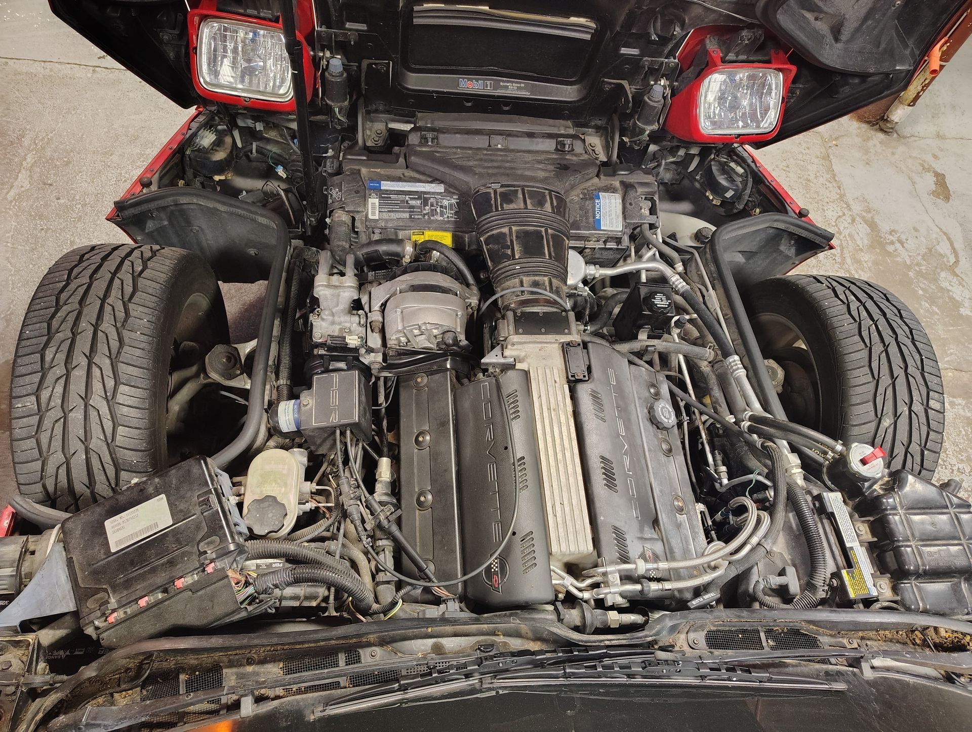 Red car's open hood reveals engine parts, tires, and headlights | MJ Auto Repair