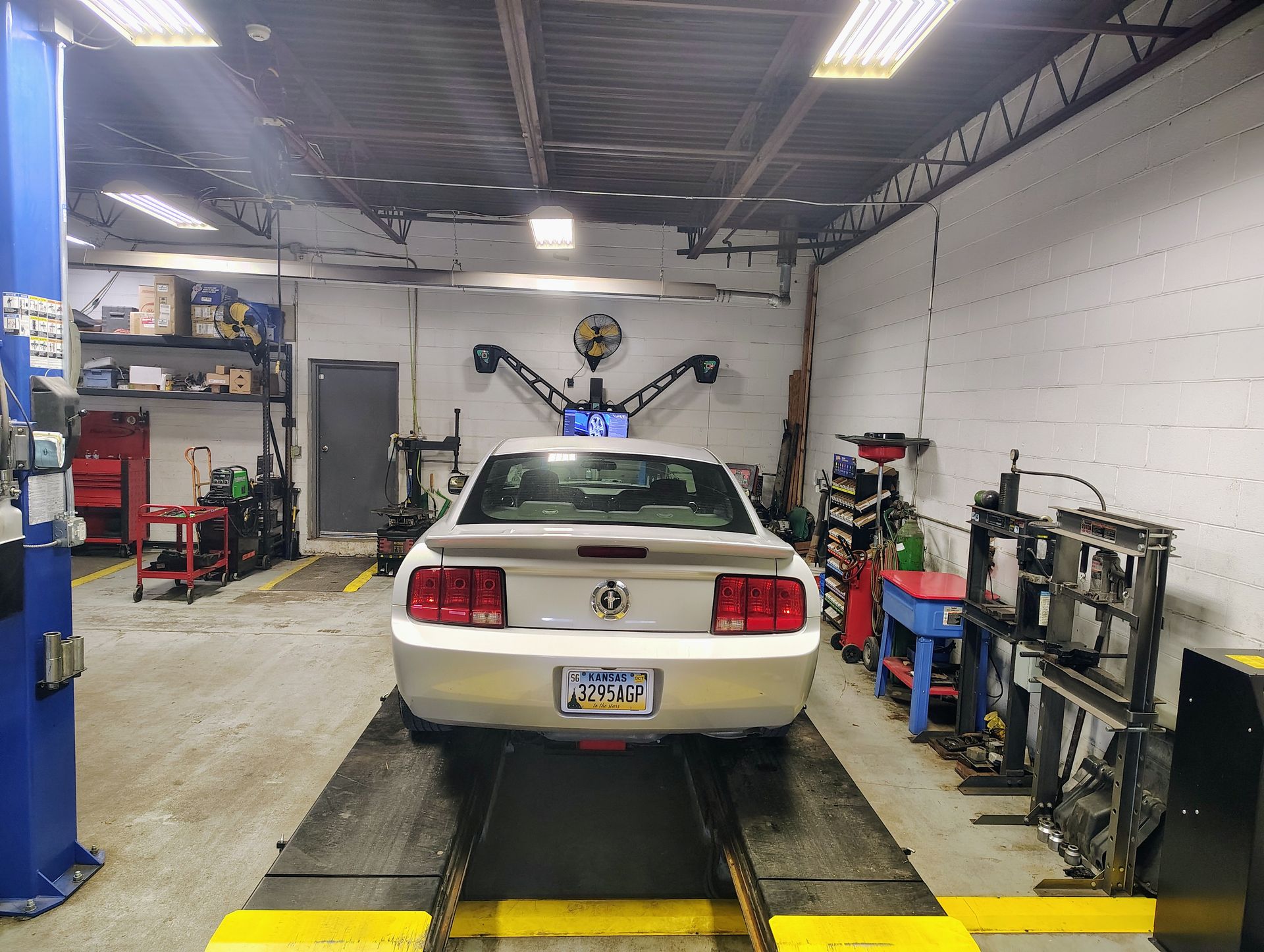 Silver car inside a car repair shop, on a lift | MJ Auto Repair
