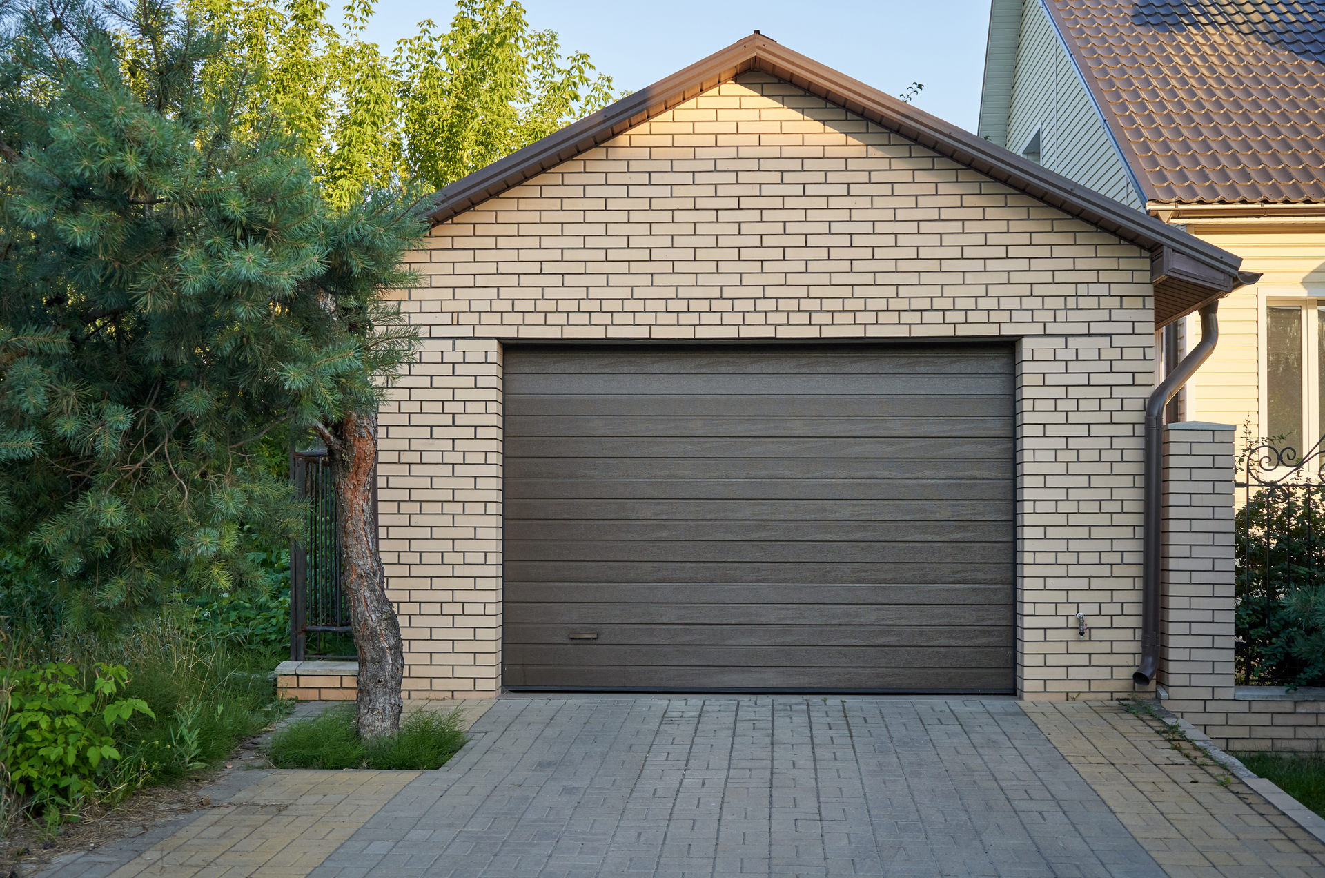 Garage with brown door and brick exterior; driveway in front.