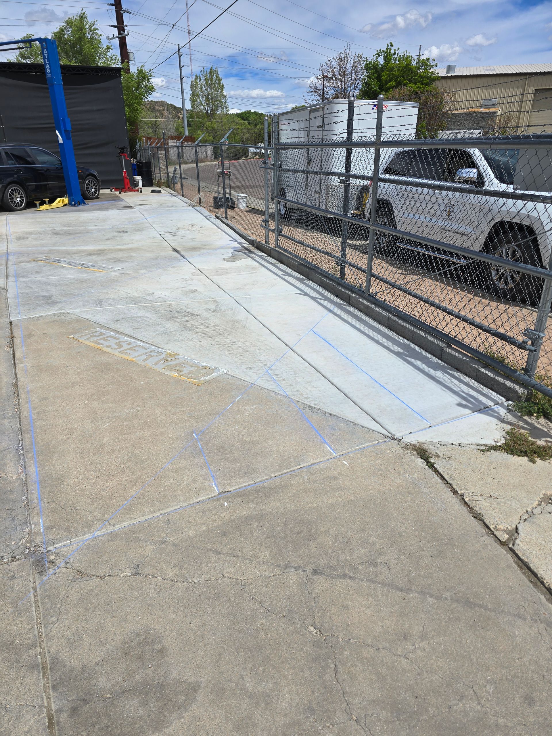 A yellow road roller compacts freshly laid asphalt on a construction site next to an orange traffic cone.