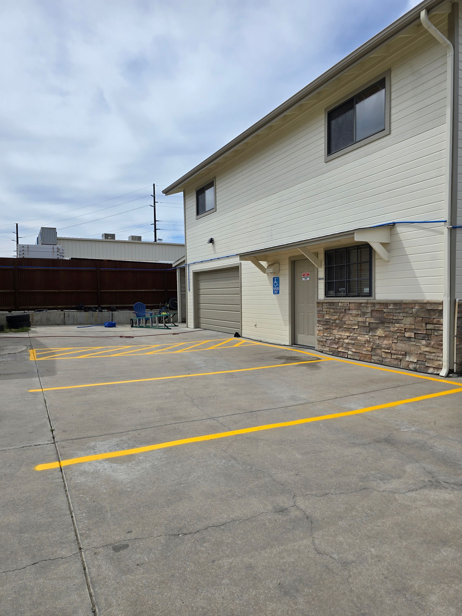 Parking lot beside a beige building with yellow-lined spaces and a cloudy sky.