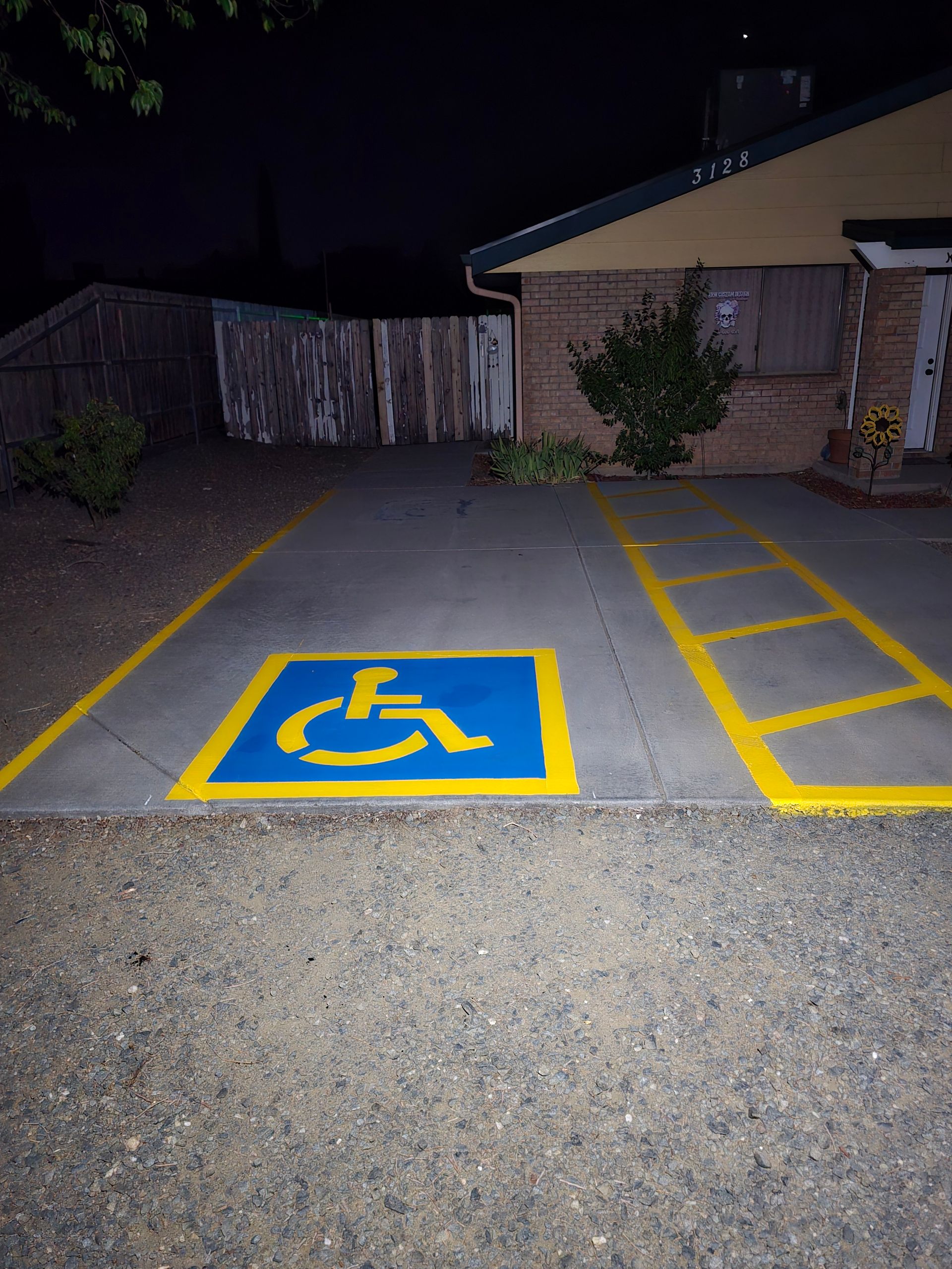 Accessible parking space with yellow markings and wheelchair symbol in a dimly lit lot