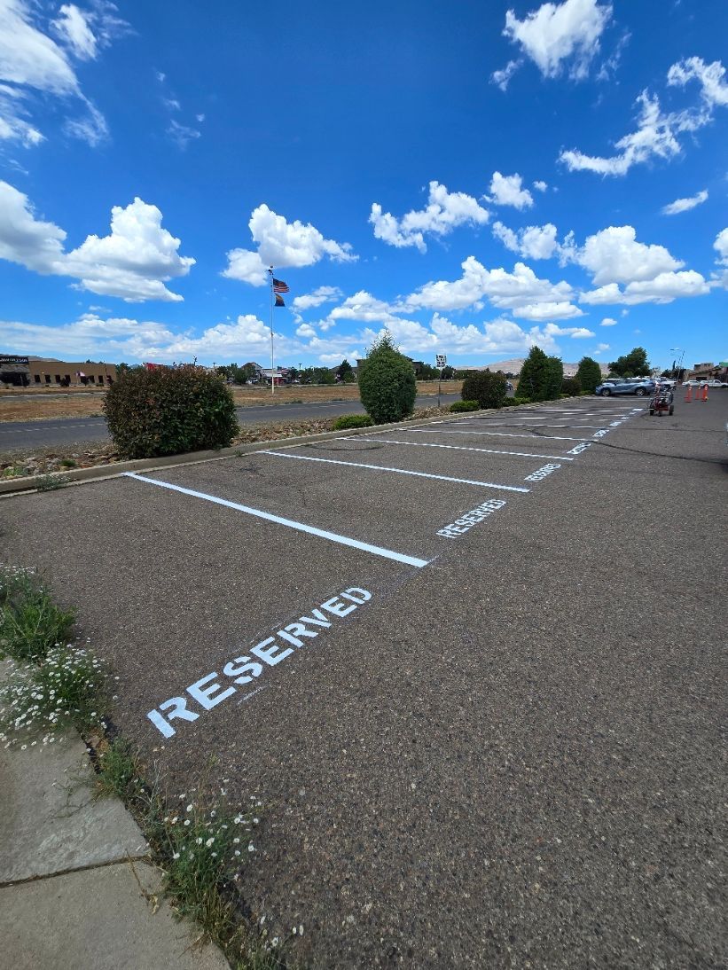 Reserved parking spaces in an empty gravel lot under a blue sky with clouds