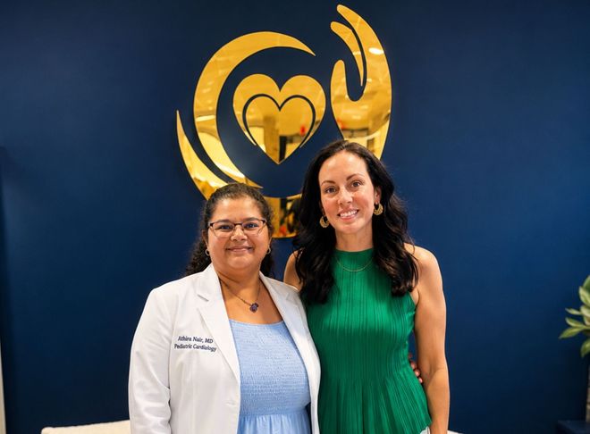 Two people standing beside a Midtown Medical sign outside a white building