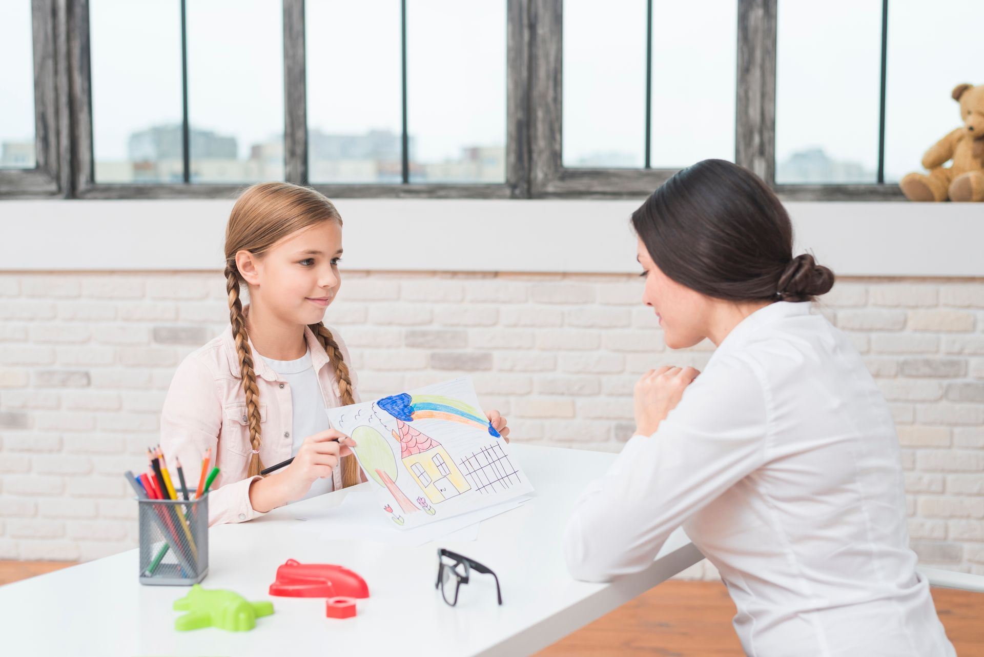 Adult and child coloring together at a table in a bright classroom