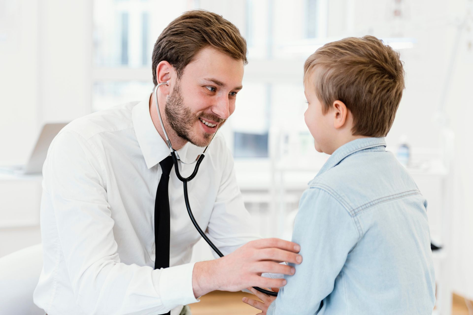 Doctor examining a child with a stethoscope in a bright clinic room