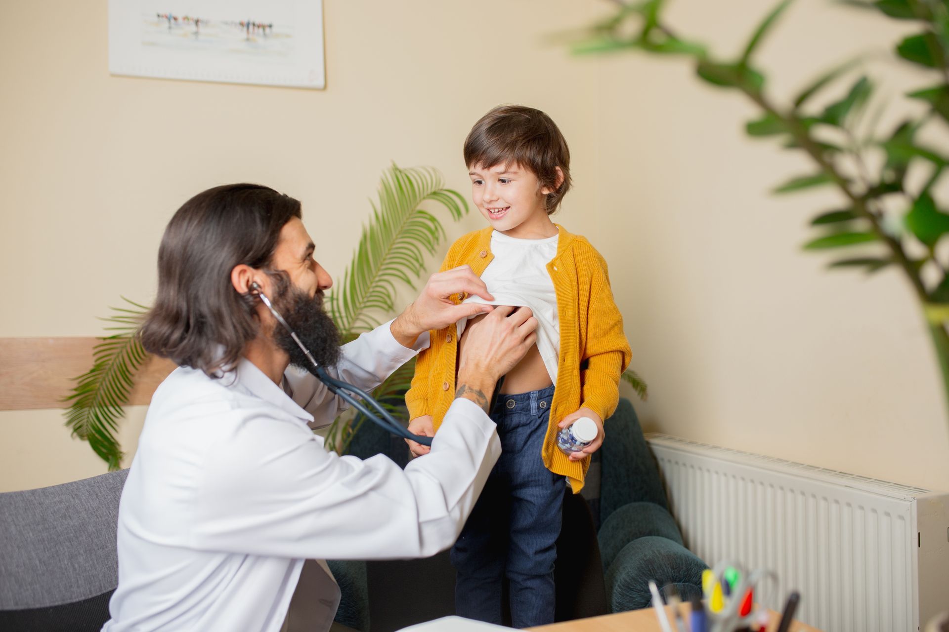 Doctor examining smiling child with stethoscope in a bright clinic room