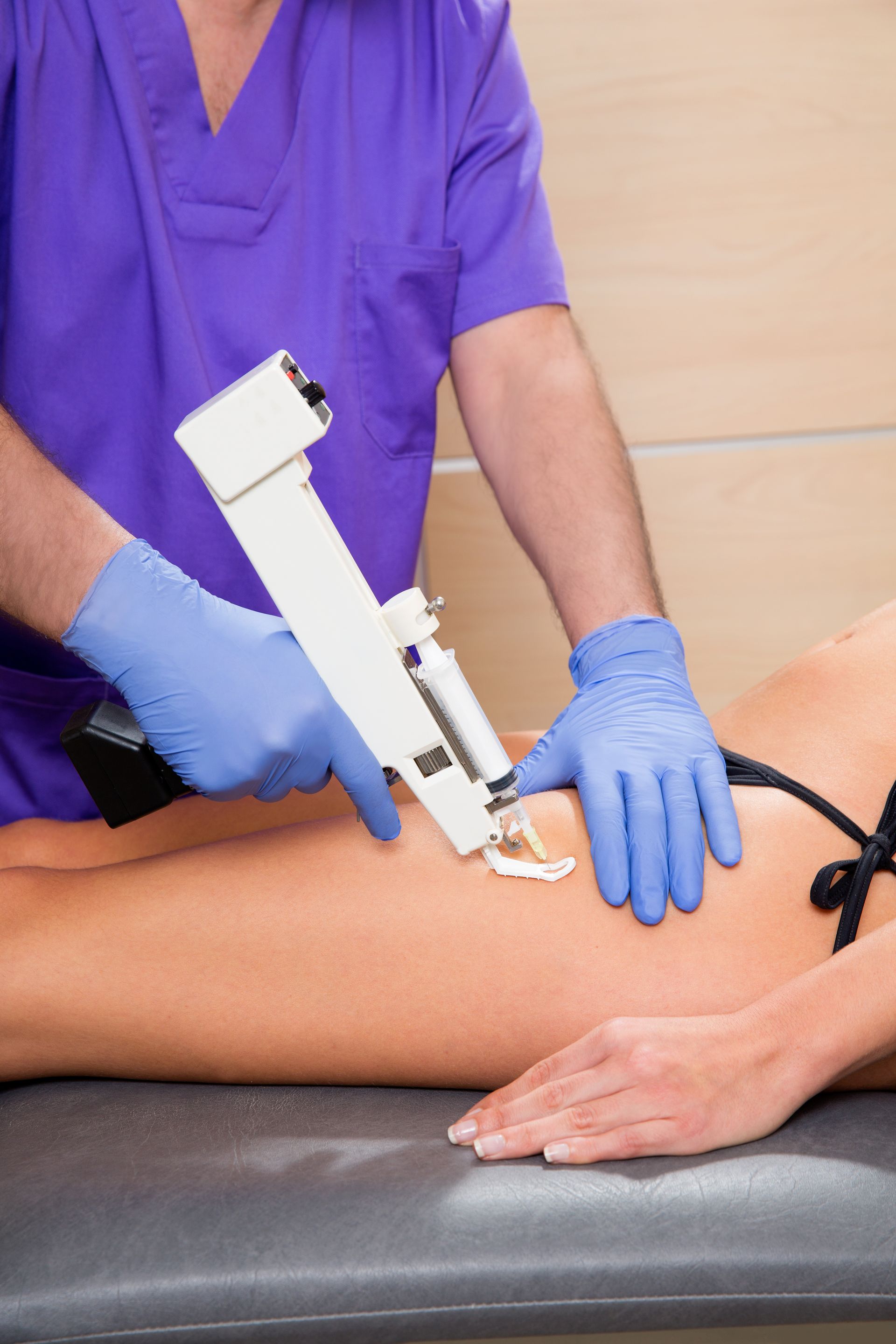 Nurse using a handheld device on a patient’s thigh in a clinical exam room