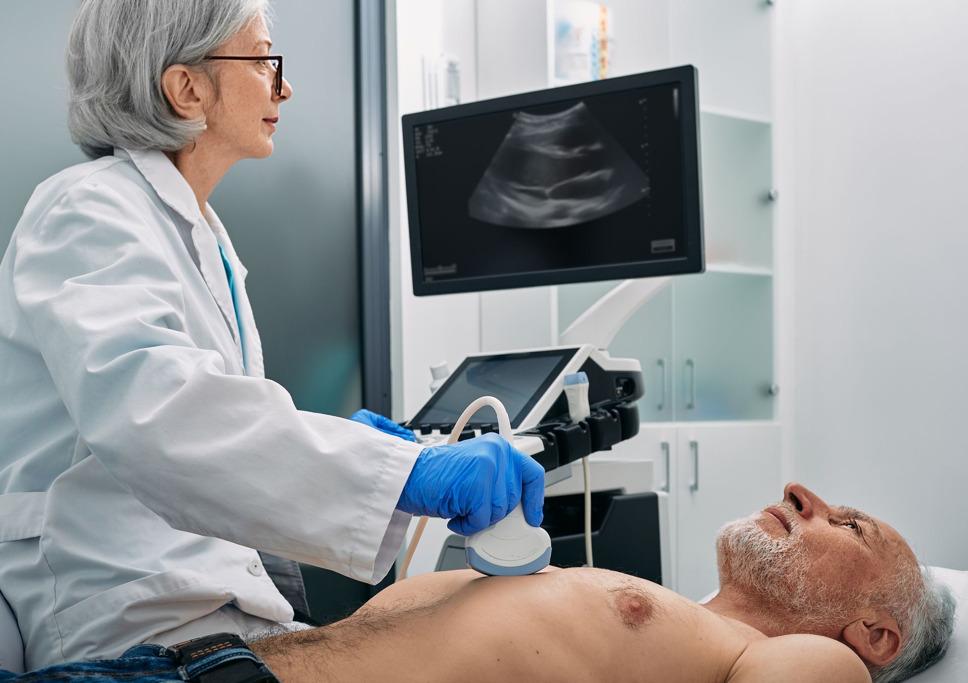Doctor performing an ultrasound on a patient in a clinic, with scan image on monitor