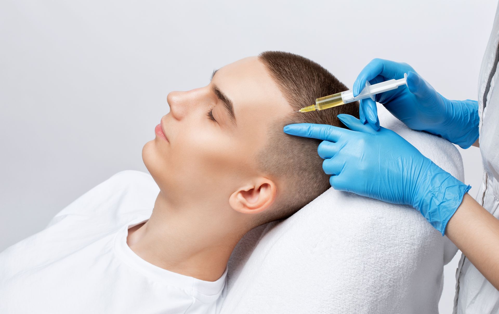 Person receiving cosmetic facial injections from a clinician wearing blue gloves