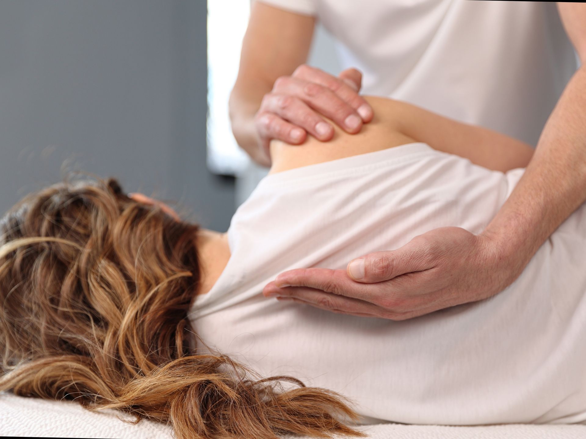 Massage therapist pressing a client’s shoulder and back during a treatment session