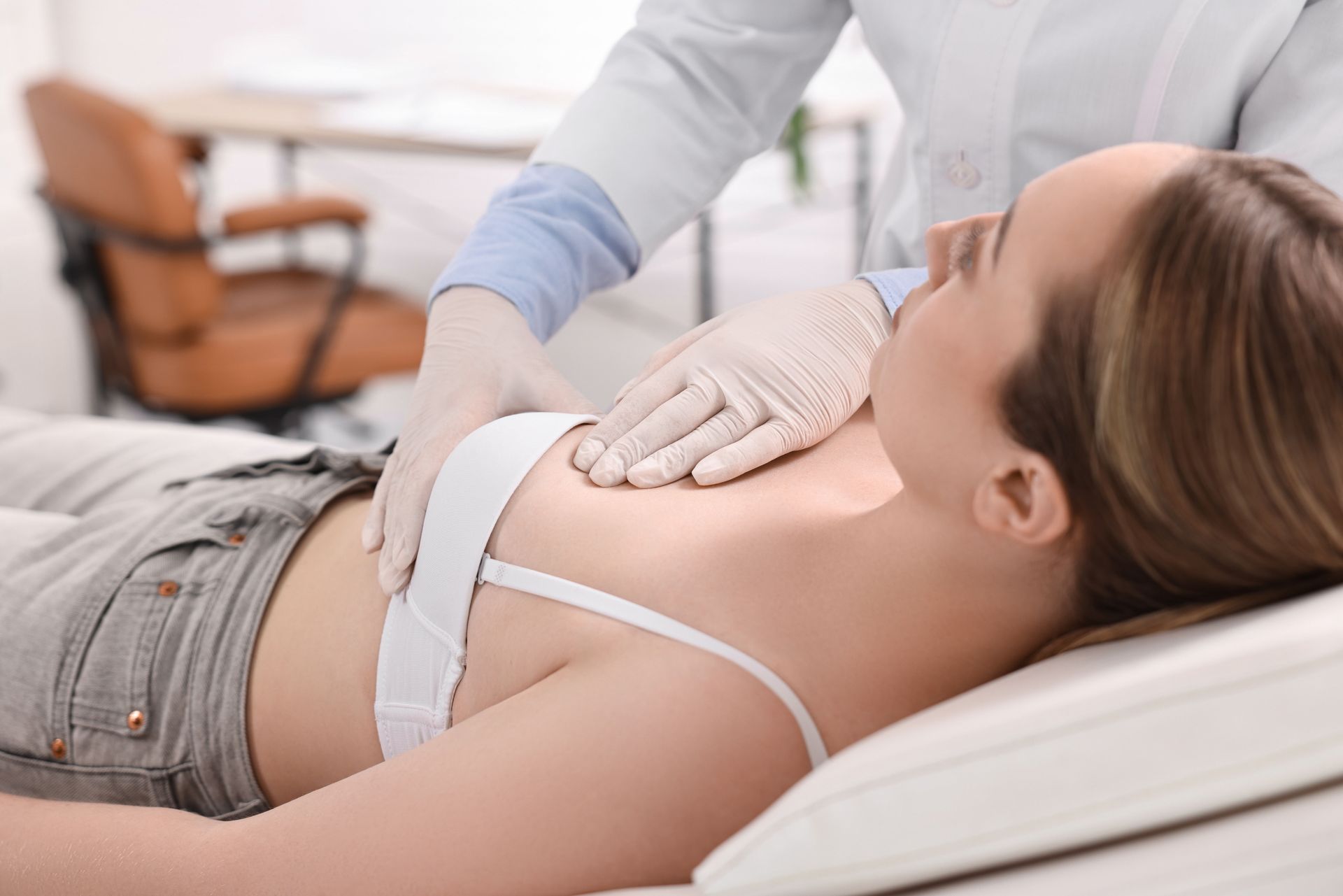 Medical professional palpating a patient’s abdomen on an exam table