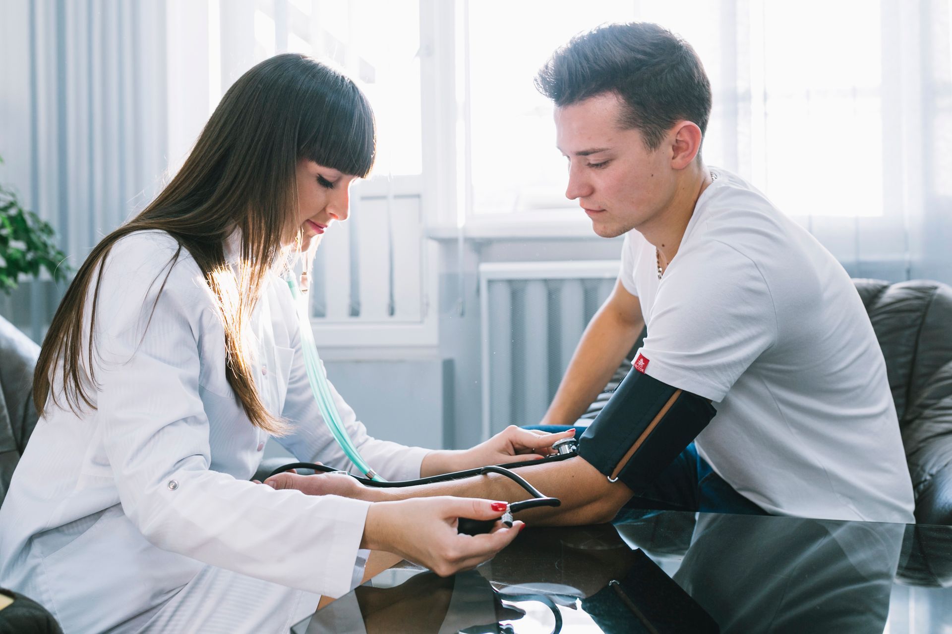 Two people checking a blood pressure reading in a bright clinic waiting room