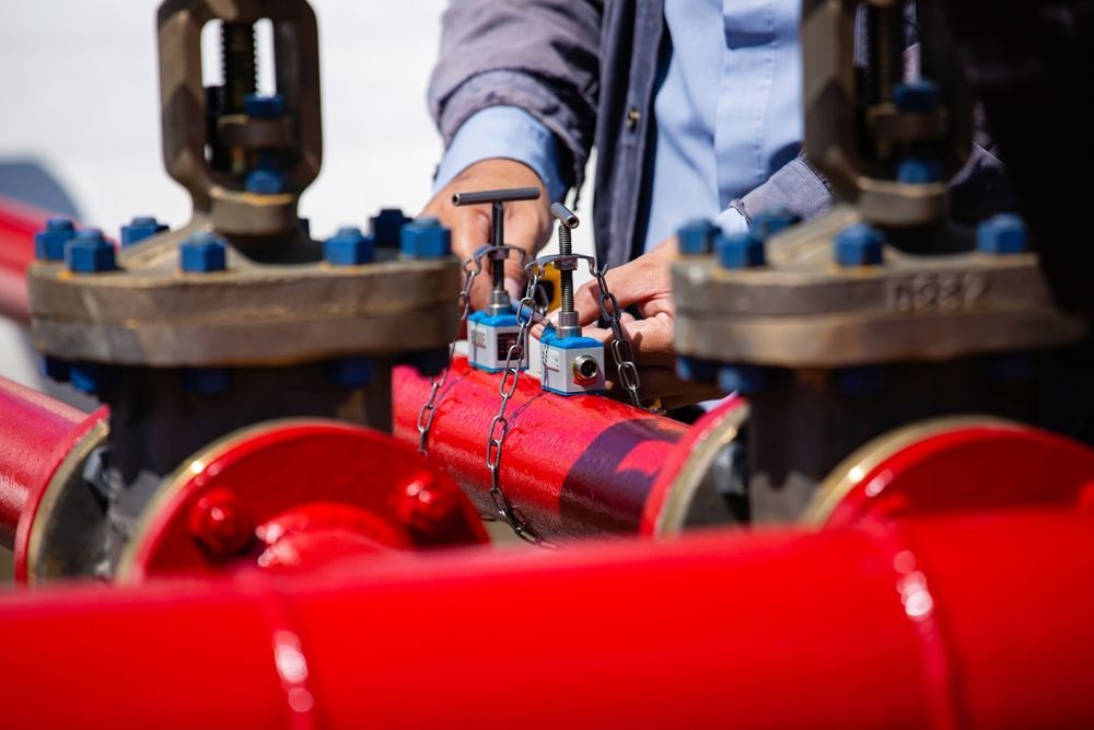 A Man is Working on a Red Pipe With a Wrench — The Pump Doctor In Kuluin, QLD