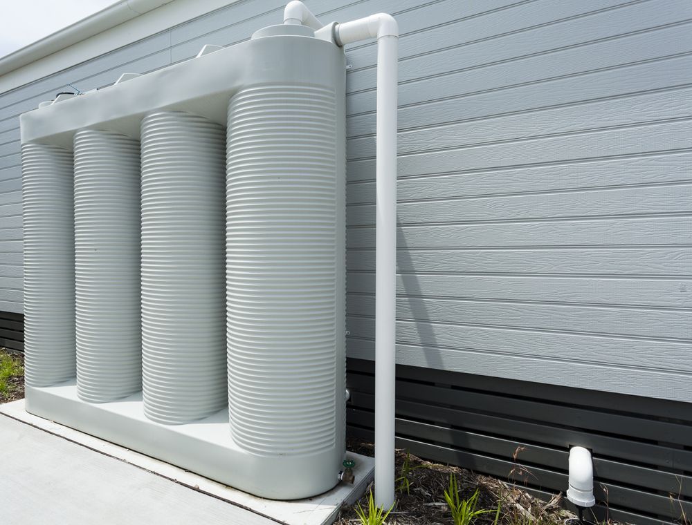 A White Water Tank is Attached to the Side of a House — The Pump Doctor In Caloundra, QLD
