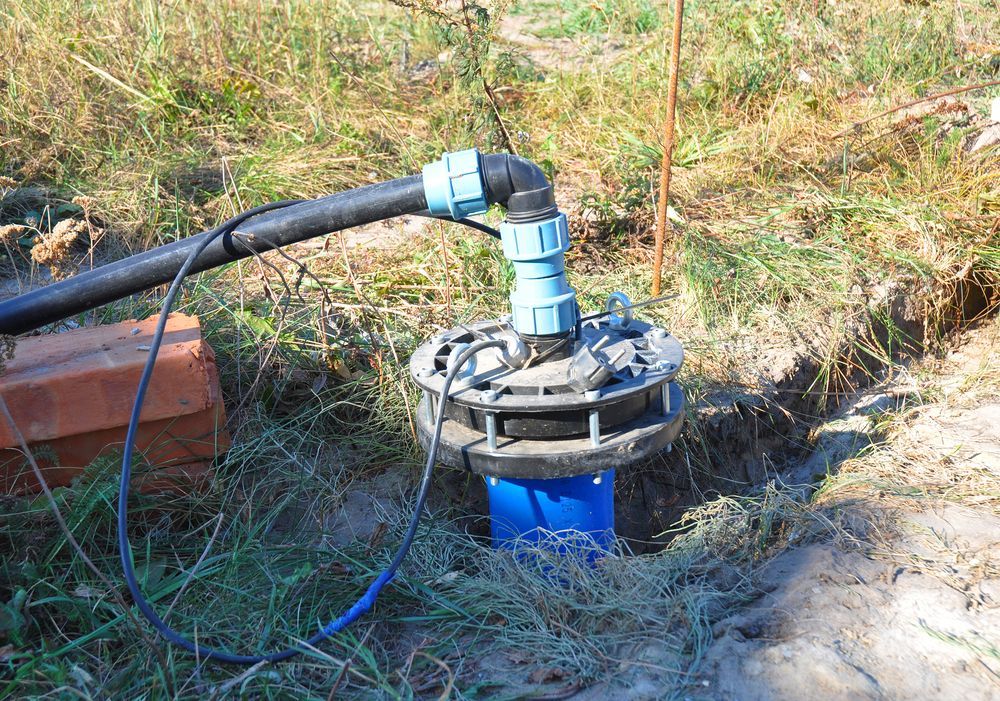 A Water Pump is Sitting in the Dirt Next to a Brick Wall — The Pump Doctor In Kuluin, QLD