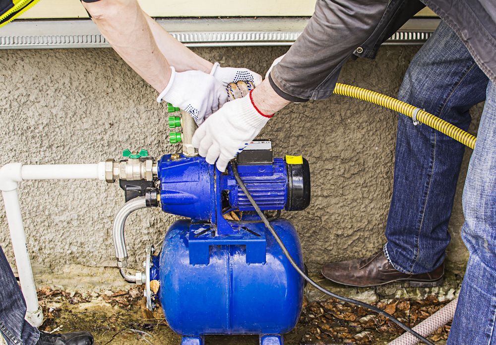 A Man is Fixing a Water Pump With a Hose — The Pump Doctor In Maroochydore, QLD