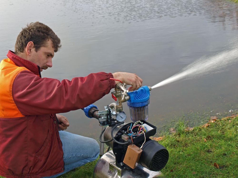 A Man is Working on a Water Pump Near a Body of Water — The Pump Doctor In Beerwah, QLD