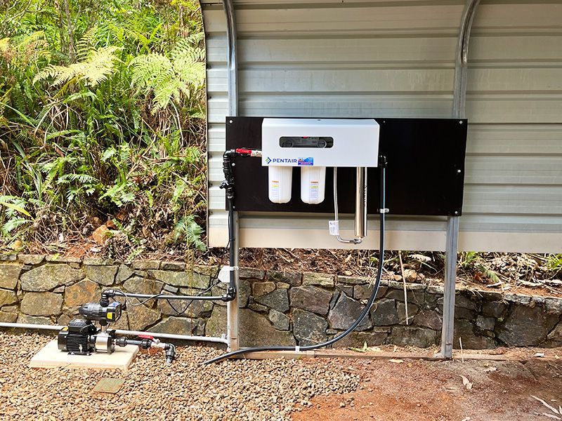 A Water Filter is Attached to the Side of a Building — The Pump Doctor In Maroochydore, QLD