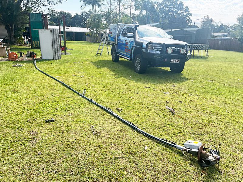 A Truck is Parked in a Grassy Field With a Hose Attached to It — The Pump Doctor In Glenview, QLD