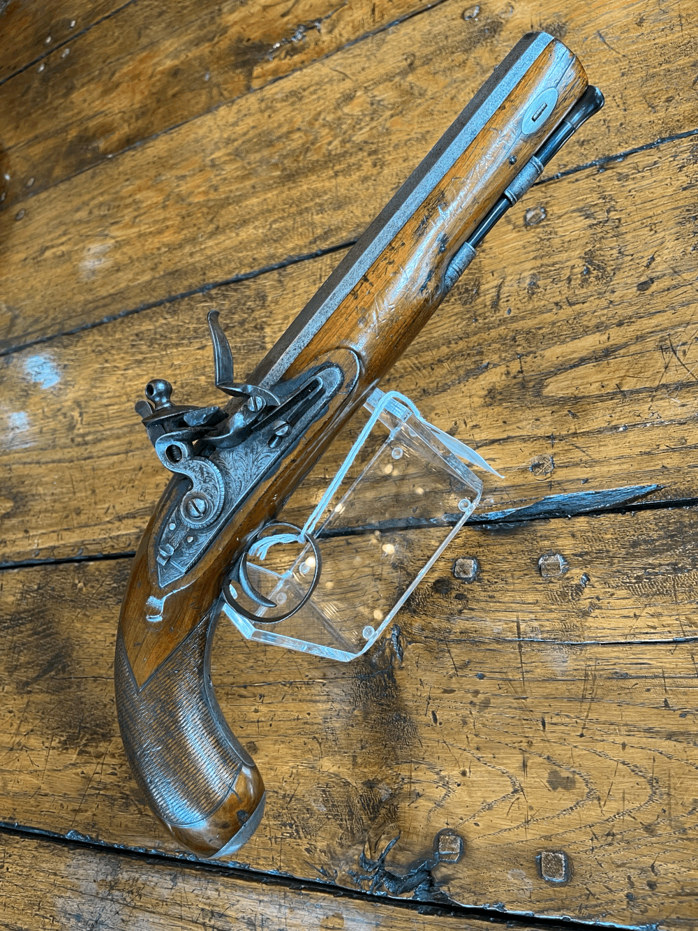 An antique flintlock pistol is sitting on a wooden table.