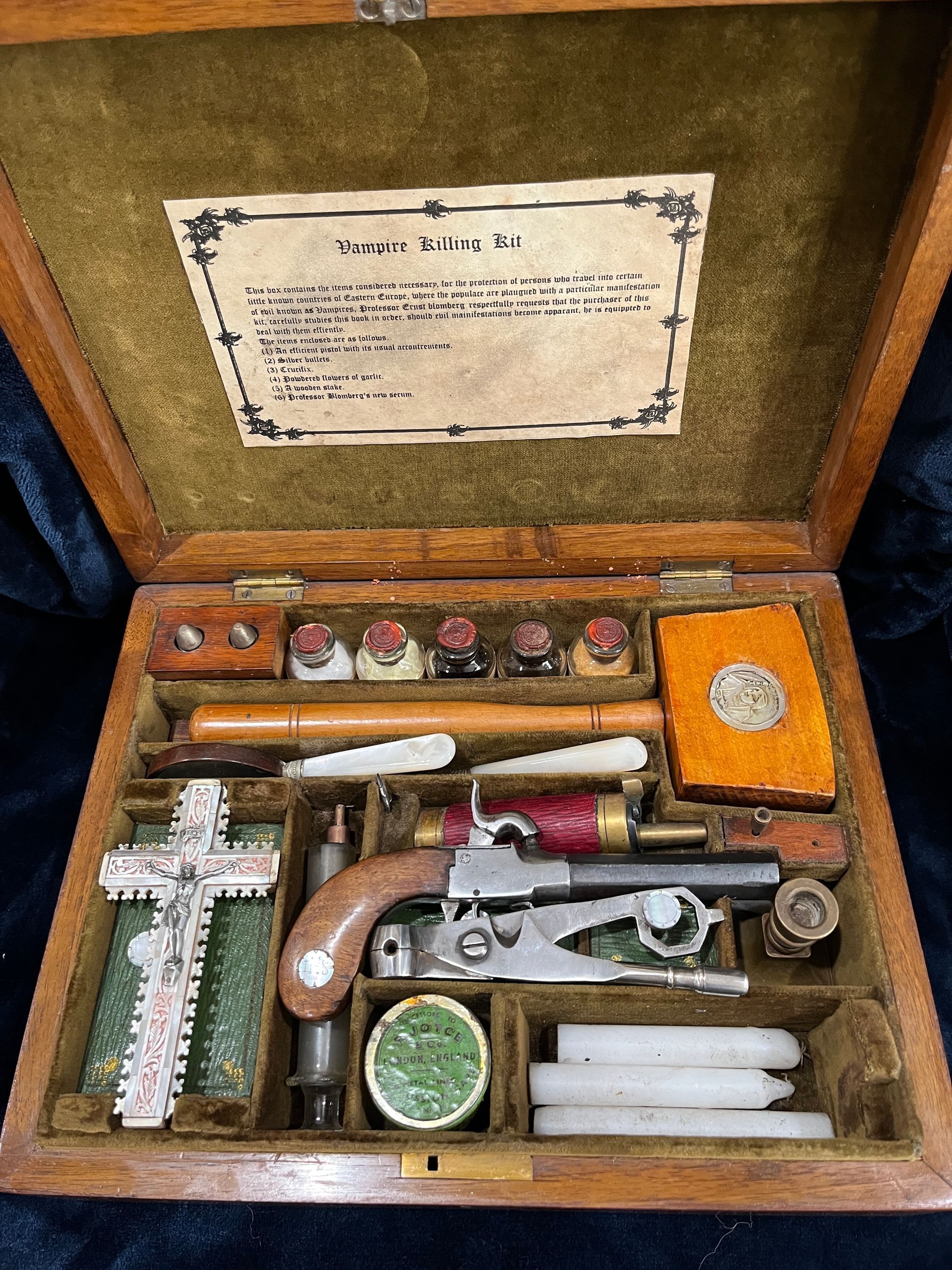 Wooden vampire kit; includes a pistol, cross, vials, and other tools, in a felt-lined wooden box.